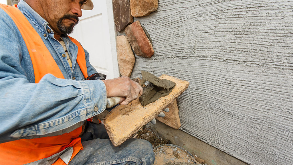 Shown in this picture is the placing of mortar by “buttering” the back of the adhered masonry veneer unit.