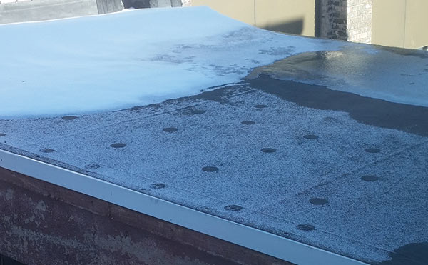 Metal roofing plates transposing through roofing membrane and melting snow due to thermal bridging.
